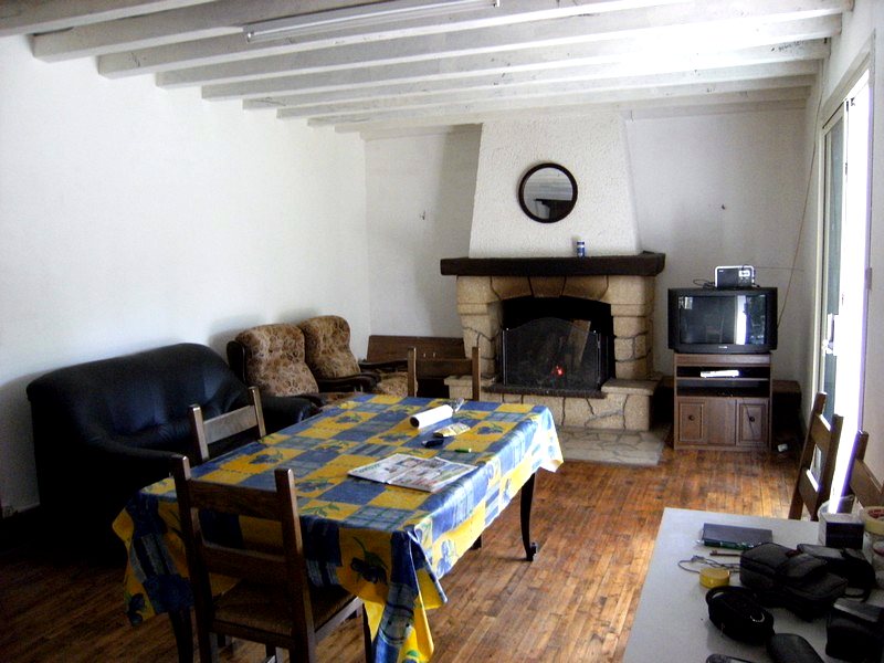Séjour de la maison avec cheminée de pierre, poutres blanches et parquet — maison à vendre avec étang et forêt en Charente