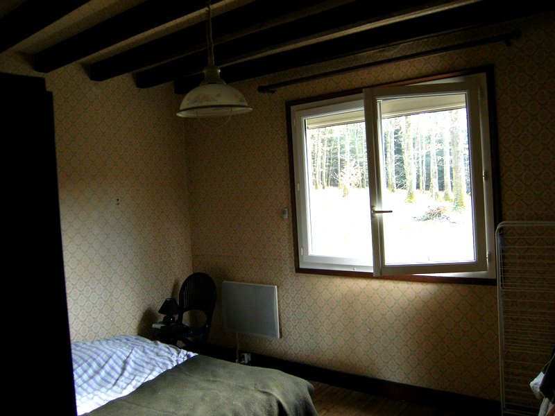 Chambre de la maison avec poutres apparentes et large fenêtre ouverte sur la forêt — maison à vendre avec étang et forêt en Charente