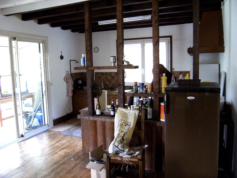 Cuisine ouverte de la maison avec poutres apparentes, parquet et grande baie vitrée — maison à vendre avec étang et forêt en Charente