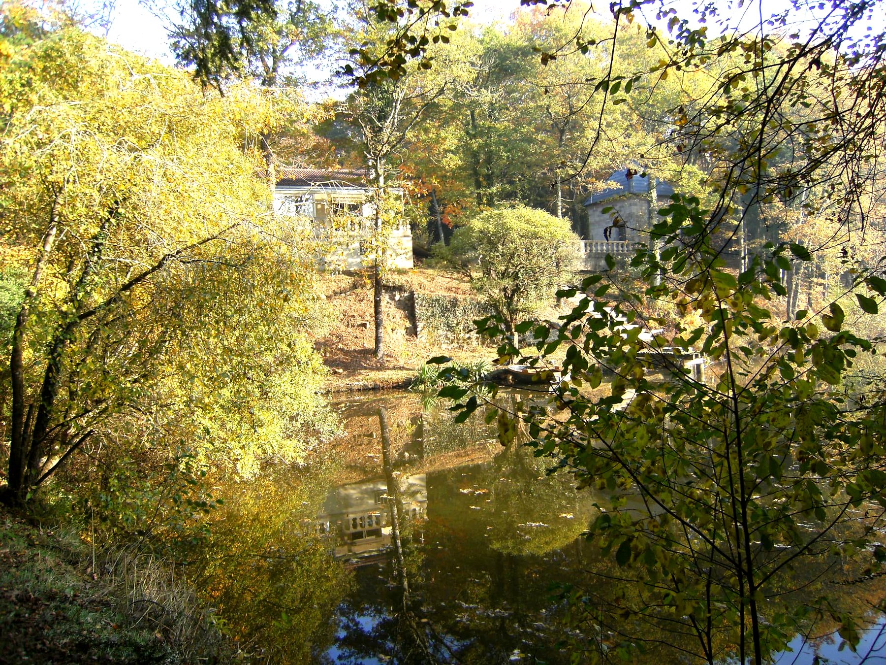 La maison et sa véranda vues depuis la rive opposée — maison à vendre avec étang et forêt en Charente