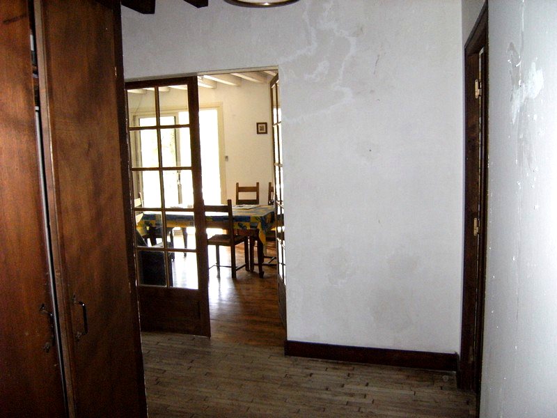 Enfilade des pièces vers la salle à manger de la maison, portes vitrées et parquet — maison à vendre avec étang et forêt en Charente